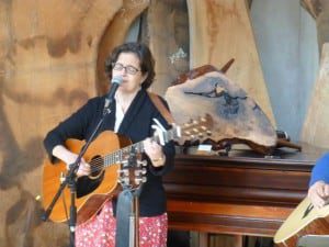 Pamela Ortiz performing with Claro Walnut Burl Stool auction item in the background.